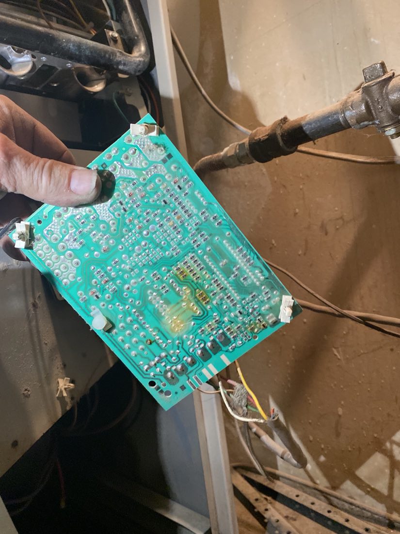 Technician holding a diagnosed furnace control board during a heating repair